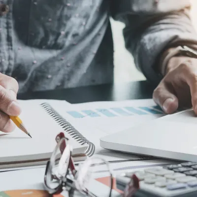 an working on laptop while taking notes