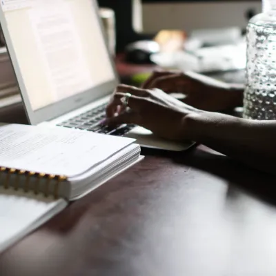 Woman typing on computer with water bottle
