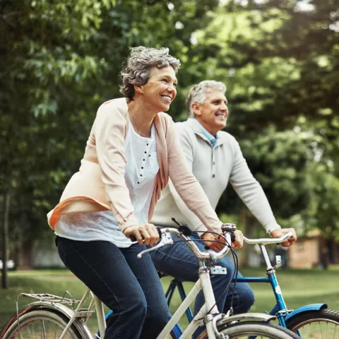 Older couple riding bikes outdoors together,