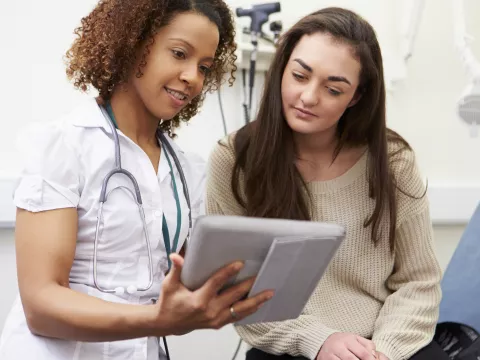 A nurse shows a young woman her test results from a preventive screening.
