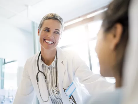A doctor greets her patient at the bedside