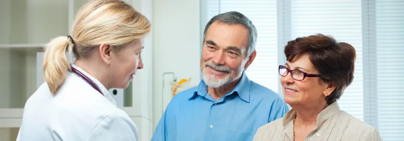A couple meets their new doctor, the woman shakes hands with the doctor.