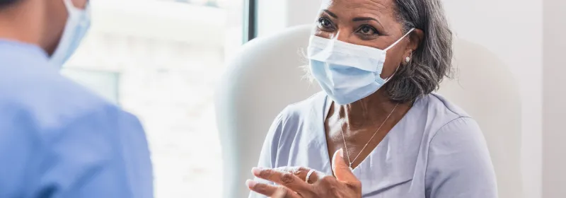 Masked Senior woman with physician